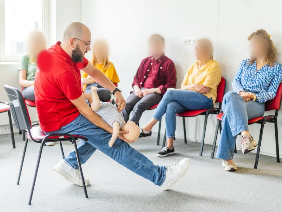 Formation en entreprise : le formateur montre les gestes à un groupe assis en cercle